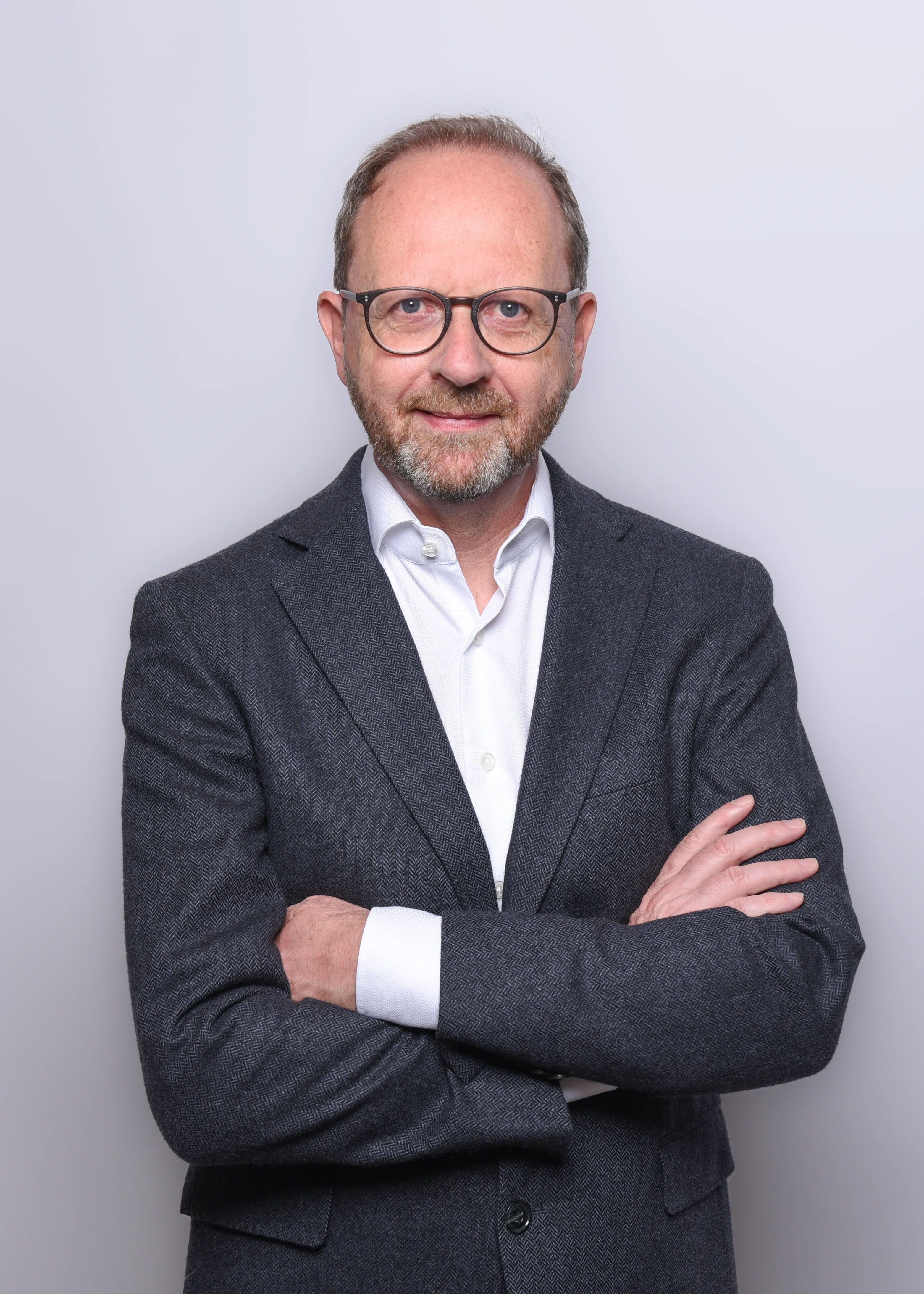 Porträtfoto von Frank Sommer: direkter Blick in die Kamera, dunkles Sakko, neutraler heller Hintergrund.